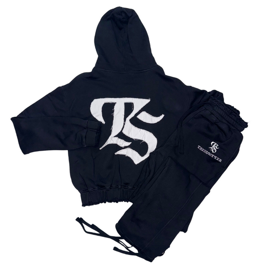 Flat lay of The Intro Set – black cropped sweatsuit with TS logo hoodie and drawstring joggers from Trendsetter Collections
